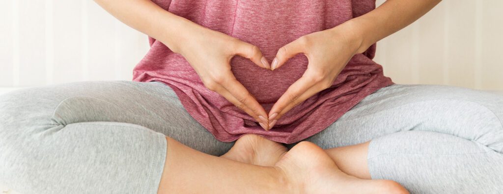 Femme formant un coeur sur son utérus