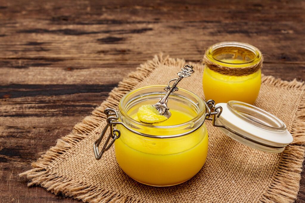 Photo de deux pots de Ghee installés sur une table en bois.