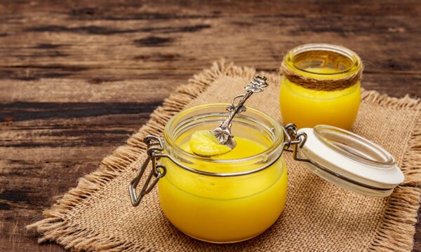 Photo de deux pots de Ghee installés sur une table en bois.