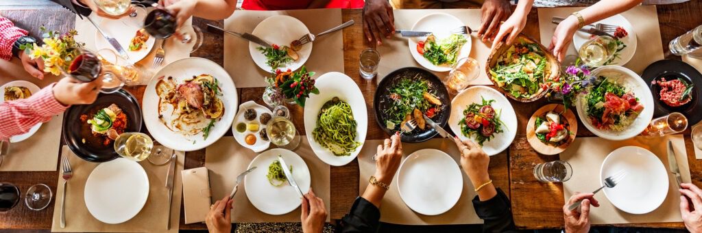 Photo représentant une grande tablée avec des assiettes remplies d'aliments colorés