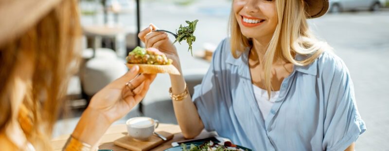 AdobeStock_286056171 Photo d'une femme en train de manger au restaurant avec une amie