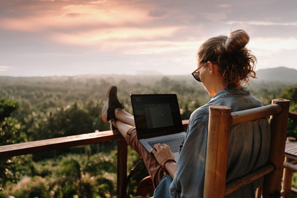 Photo d'une femme sur son ordinateur face à un paysage de nature